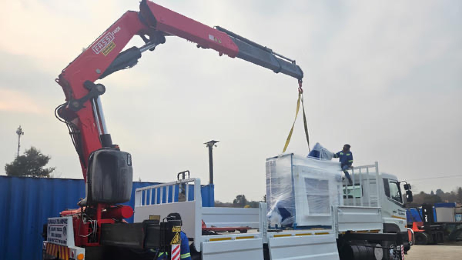 Crane lifting wrapped machine onto truck
